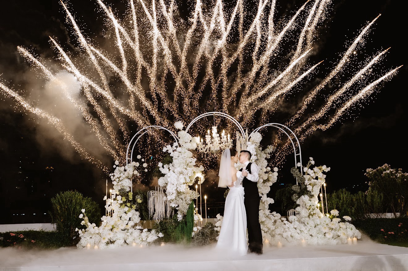 คู่บ่าวสาวจุมพิตใต้แสงดอกไม้ไฟและฉากดอกไม้สีขาว โดย Sweet Blossom Wedding Planner